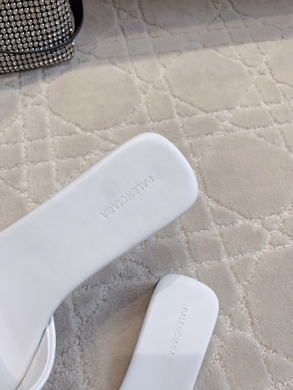 White Balenciaga slide sandals close-up showing embossed branding on footbed