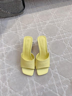 Yellow slide sandals with square toe and embossed logo on the footbed