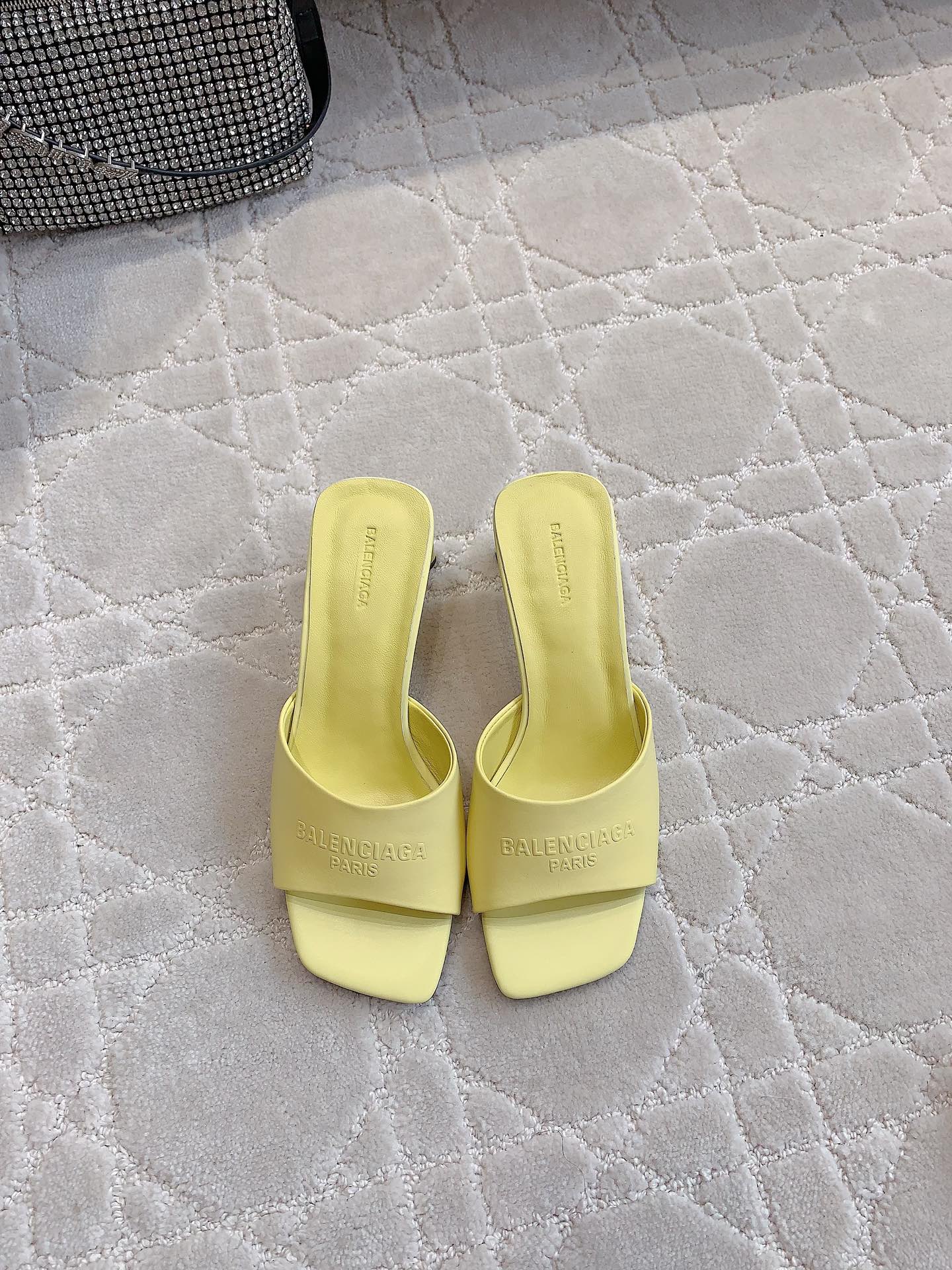 Yellow slide sandals with square toe and embossed logo on the footbed
