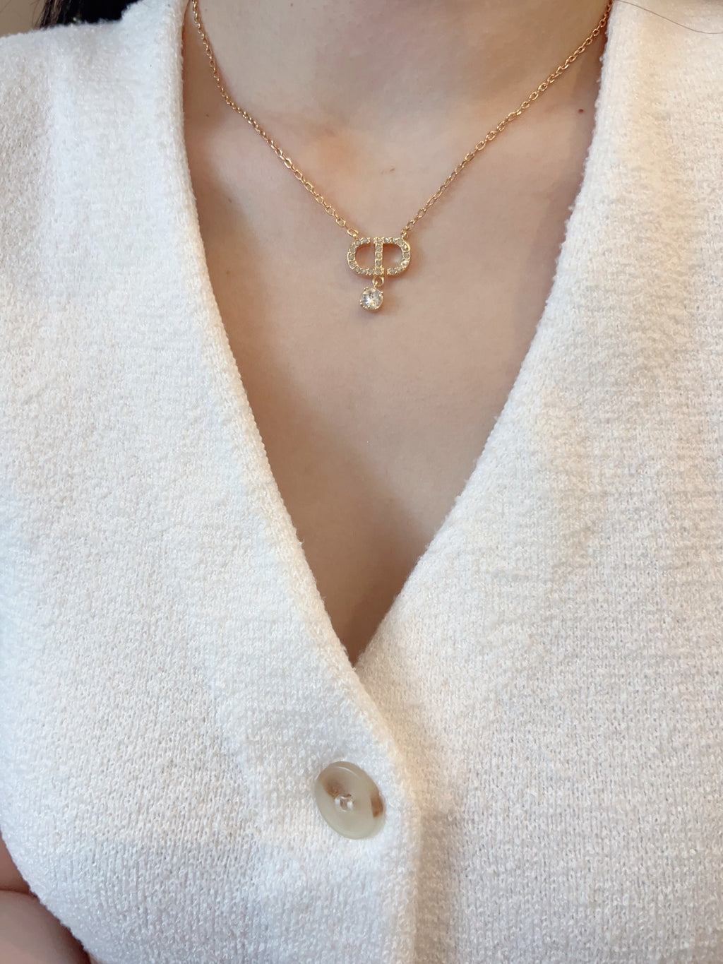 Gold-tone Dior pendant necklace on white knit top with small crystal D pendant