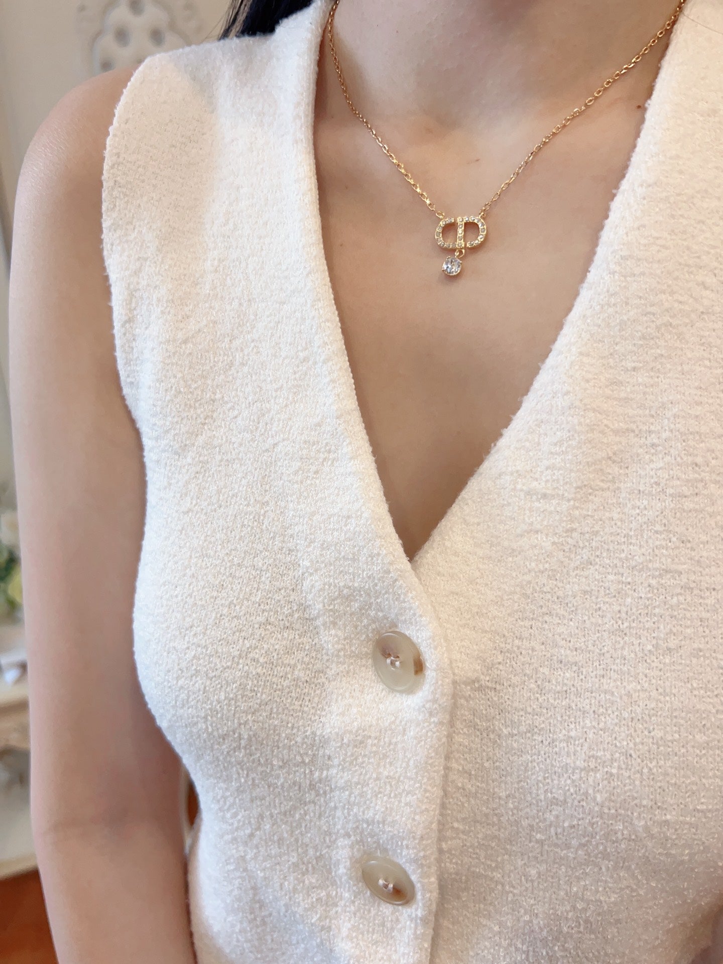 Gold-tone Dior pendant necklace on white knit top with D charm and crystal drop