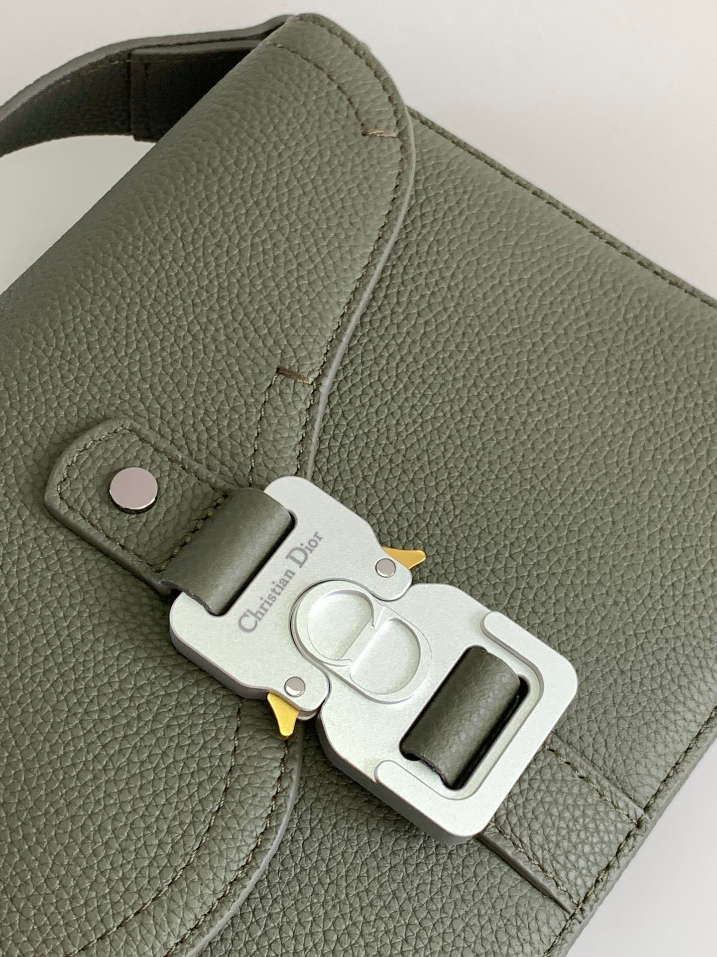 Dior men’s green leather bag close-up of front clasp and keyring detail