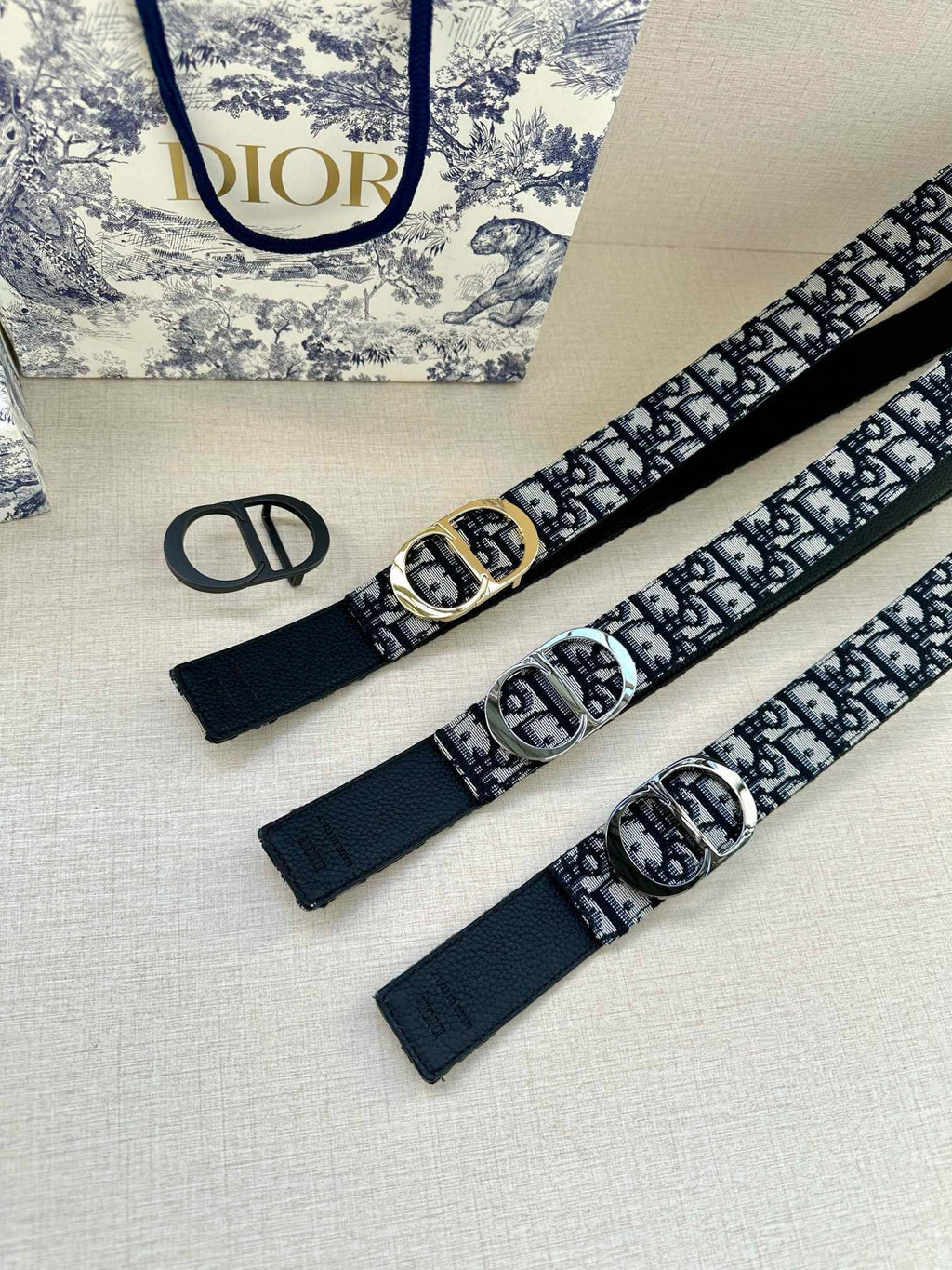 Dior monogram belt pair with navy patterned straps and silver-tone oval buckles