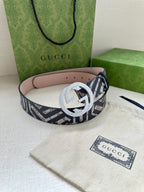 Gucci monogram belt with light grey circular buckle, navy-and-white pattern strap and pink underside