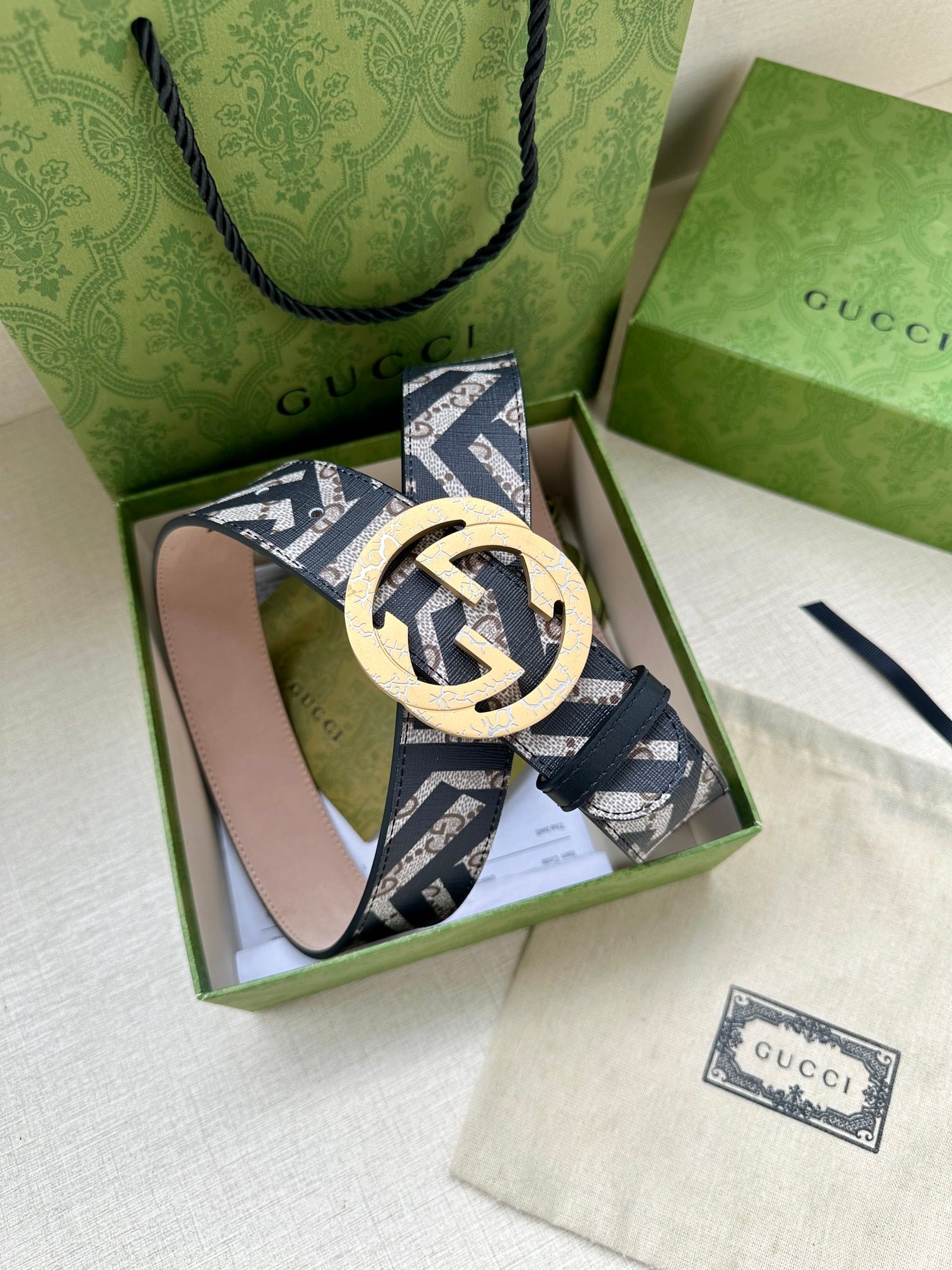 Gucci monogram belt with large gold circular buckle and navy-and-white patterned strap