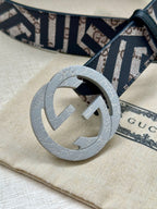 Gucci belt close-up with navy-and-white monogram strap and light grey interlocking buckle