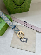 Gucci belt close-up of light pink underside and GG canvas strap with gold circular buckle.