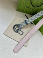 Gucci belt laid flat with light pink leather reverse, blue-trimmed GG strap, round buckle.