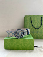 Gucci belt on box with GG canvas strap, blue trim, and gold-toned circular buckle.