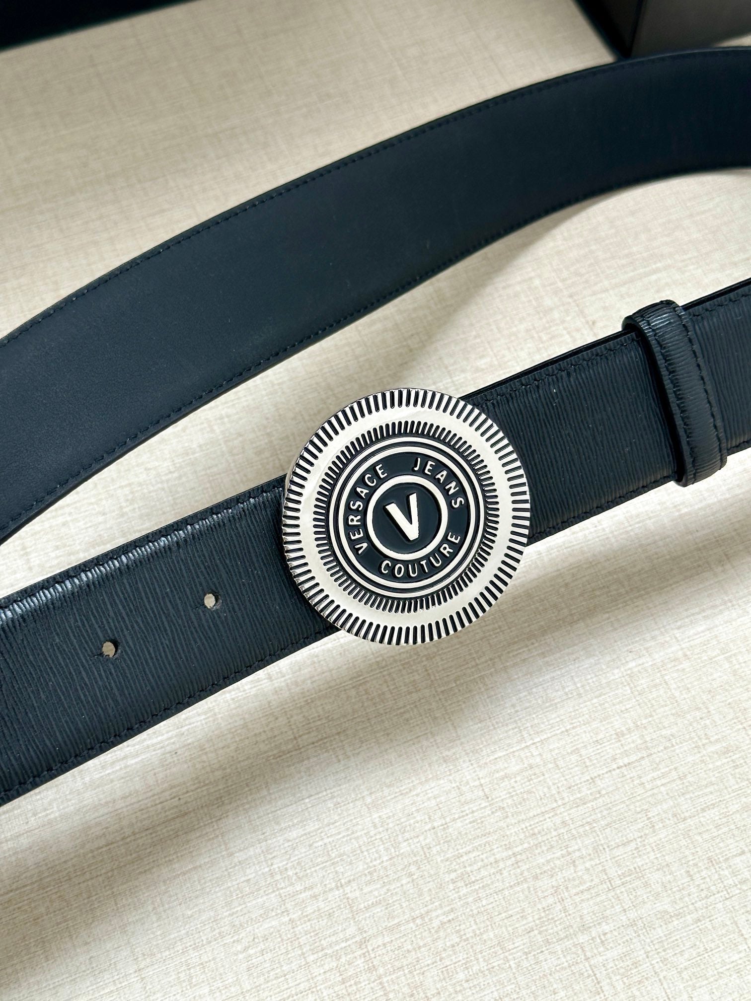 Dark blue leather belt with circular silver V-logo buckle