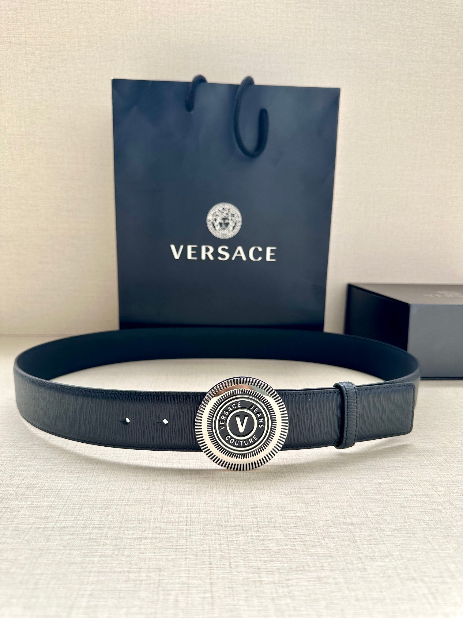 Dark blue leather belt with circular silver logo buckle