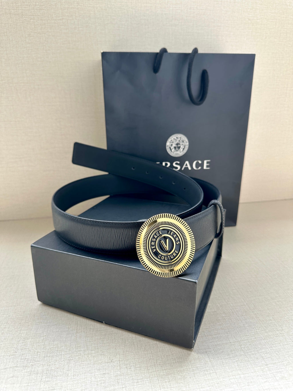 Dark blue leather belt with circular gold logo buckle