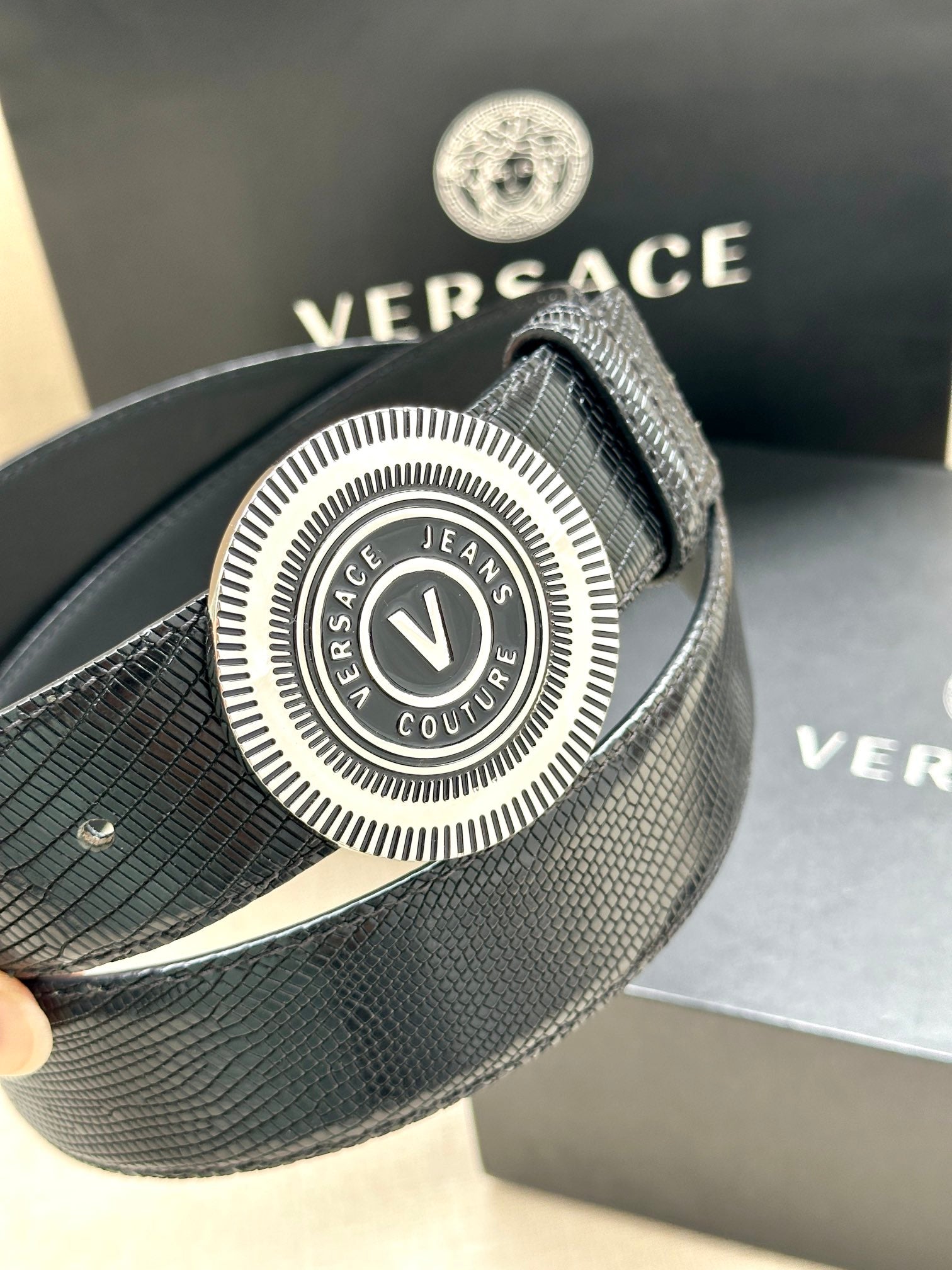 Versace Belt close-up: textured navy strap with round logo buckle