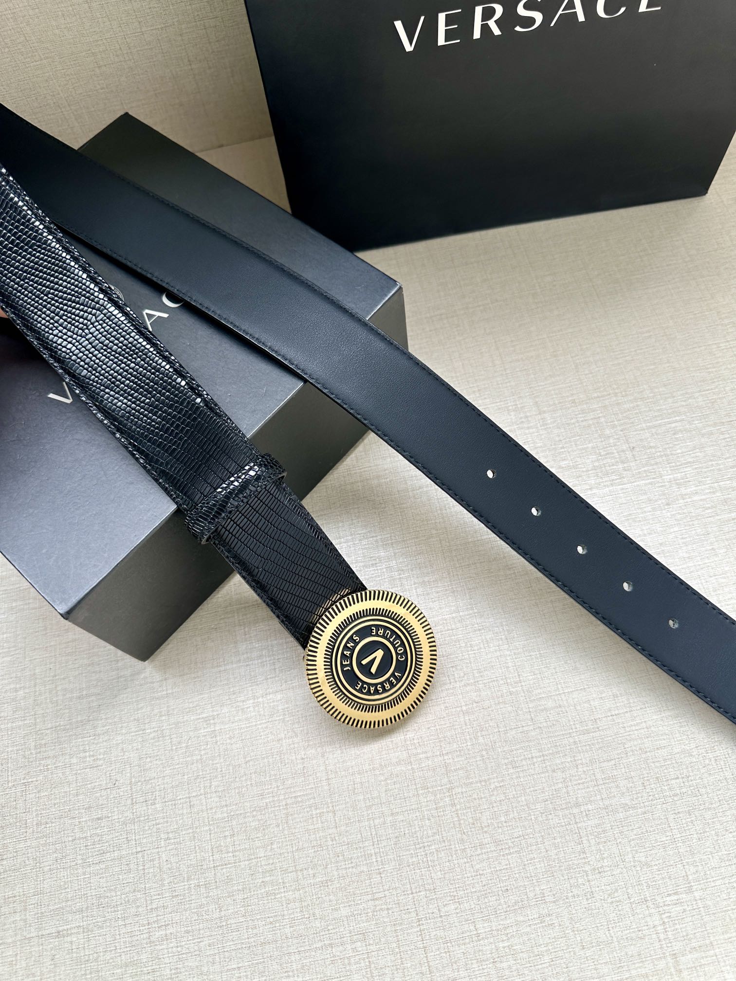 Versace Belt buckle close-up on dark navy strap with small eyelets