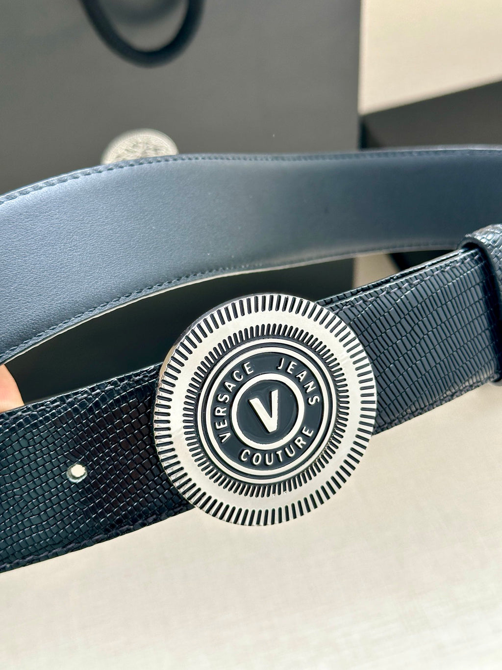 Versace Belt detail: round embossed logo buckle on textured navy strap