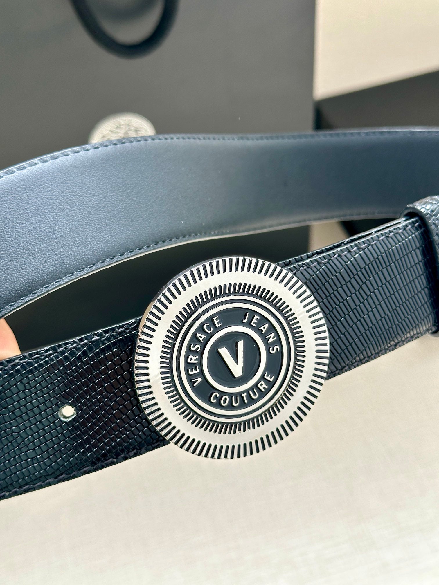 Versace Belt detail: round embossed logo buckle on textured navy strap