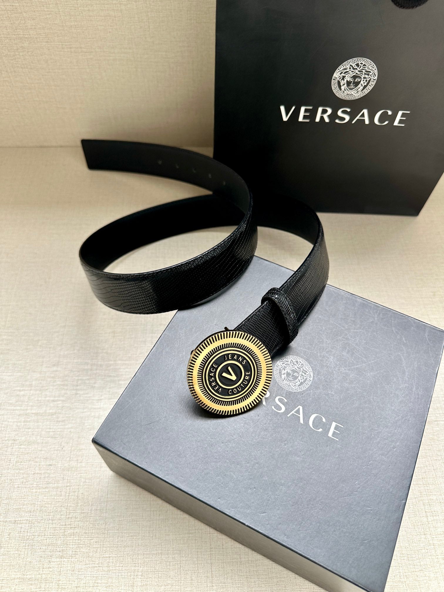 Versace Belt laid flat, black strap with gold logo medallion buckle