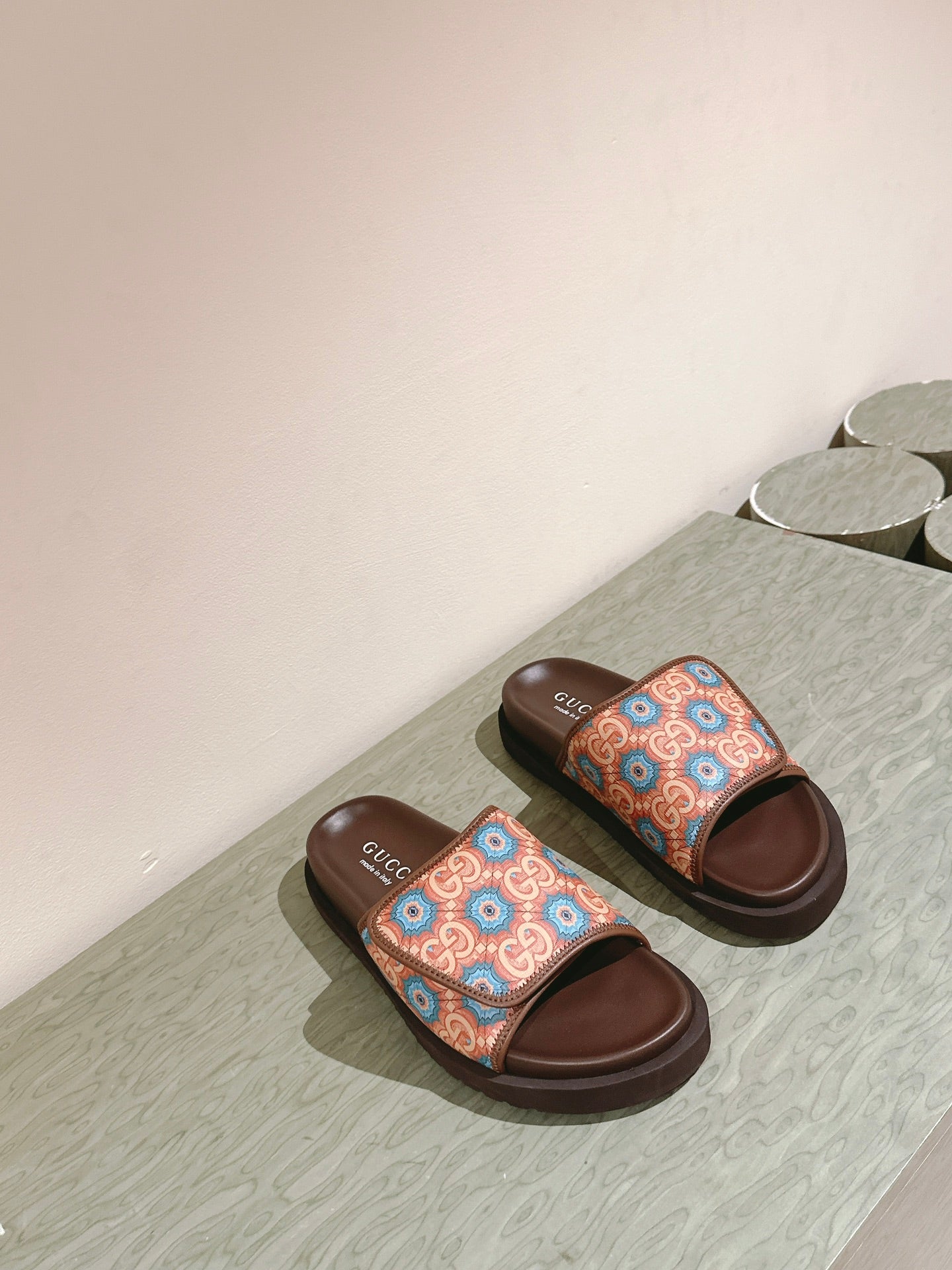 Pair of brown slide sandals with multicolor patterned straps and thick rubber soles