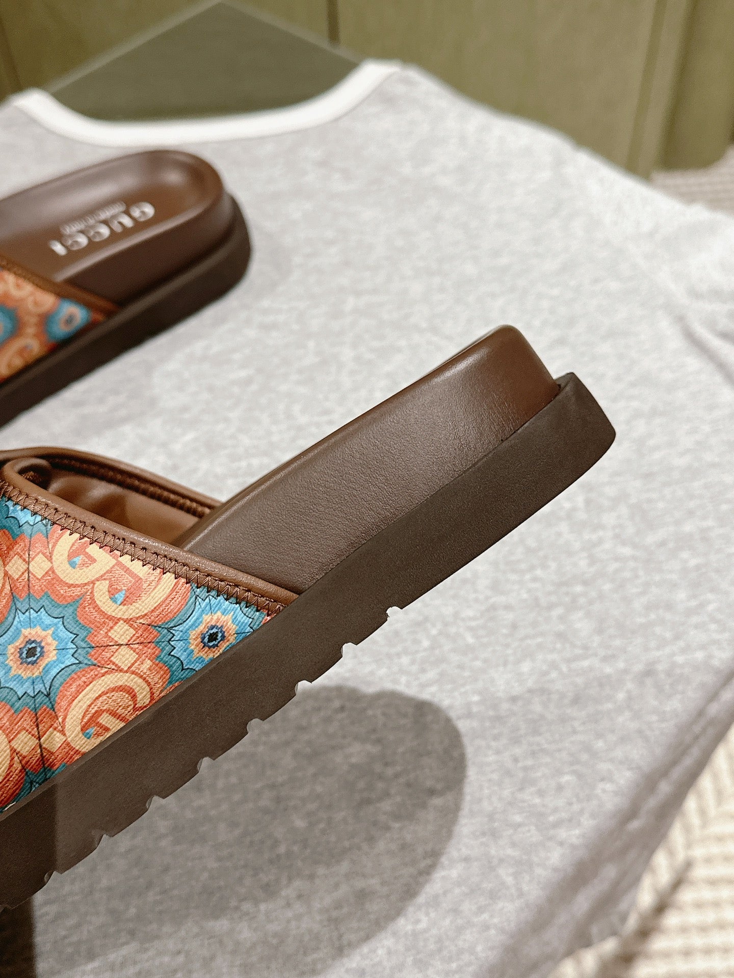 Side view of brown slide sandal with multicolor patterned strap and cushioned footbed