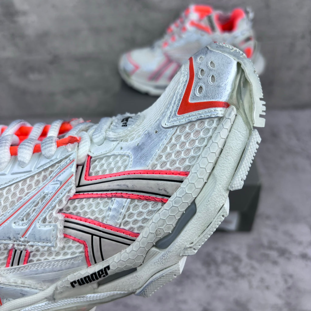 Unisex sneaker heel-side view with white mesh, red trim, and textured rubber sole