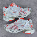 Unisex sneakers with white mesh uppers, red trim, chunky gray soles, and orange laces