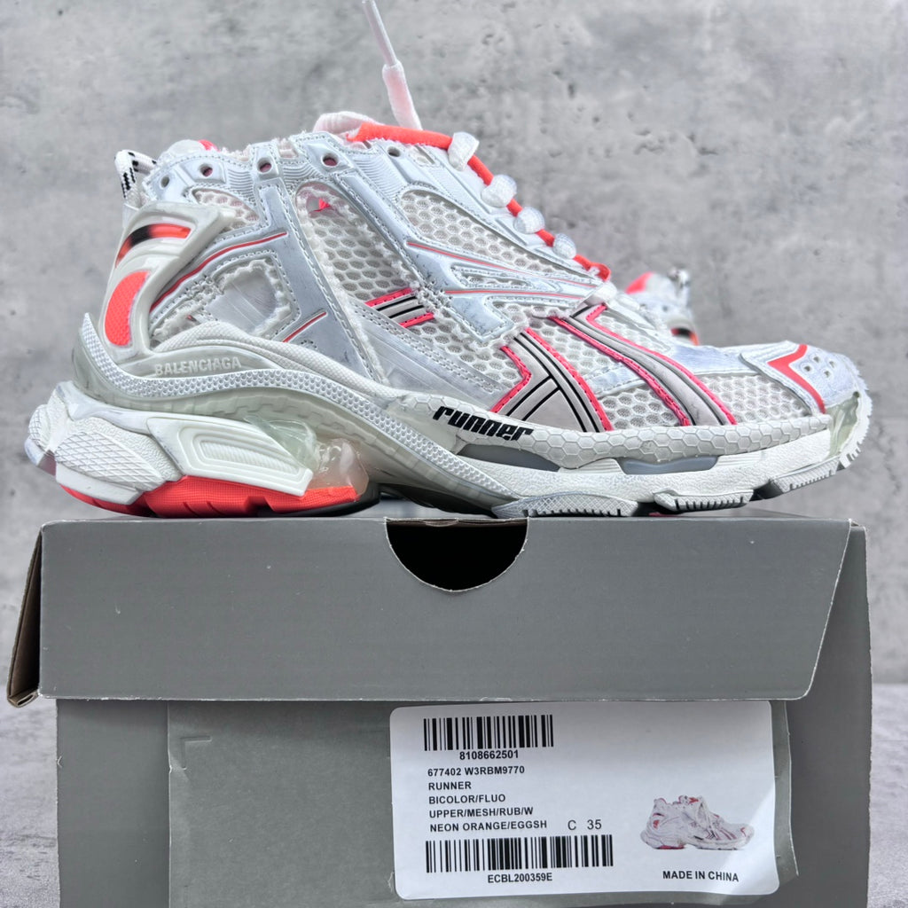 Unisex sneakers on a box; white mesh uppers with red trim and chunky treaded soles