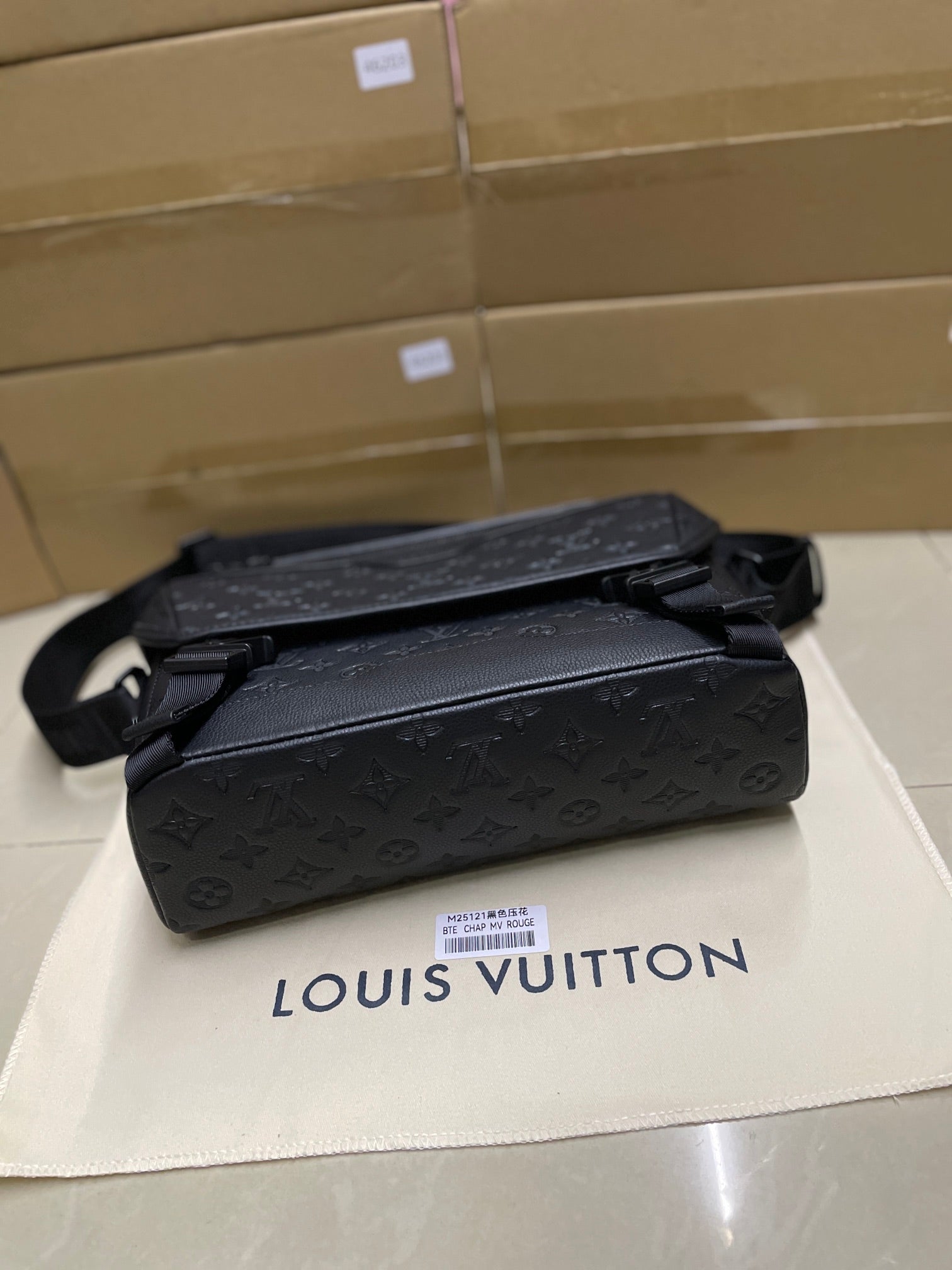 Black monogram crossbody bag with front flap, belt strap, and zip pull