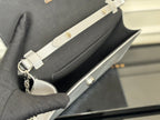 Louis Vuitton silver-gray bag shown with chain strap and clasp, held by hand