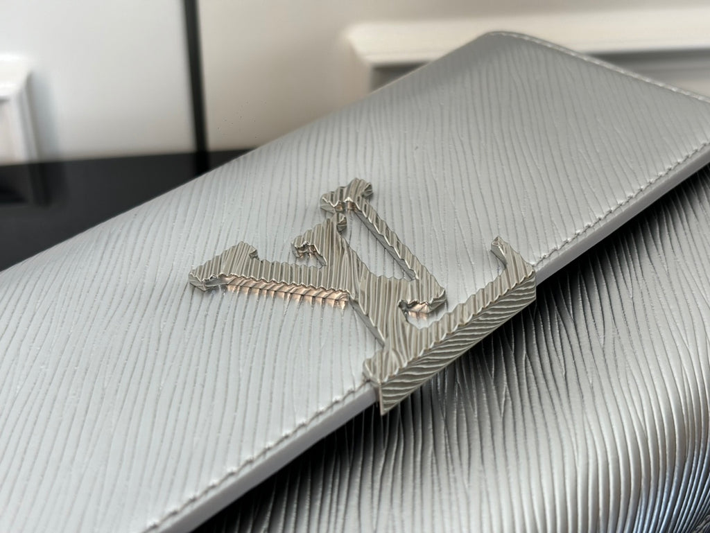 Louis Vuitton silver-gray bag close-up of metallic LV logo on textured flap