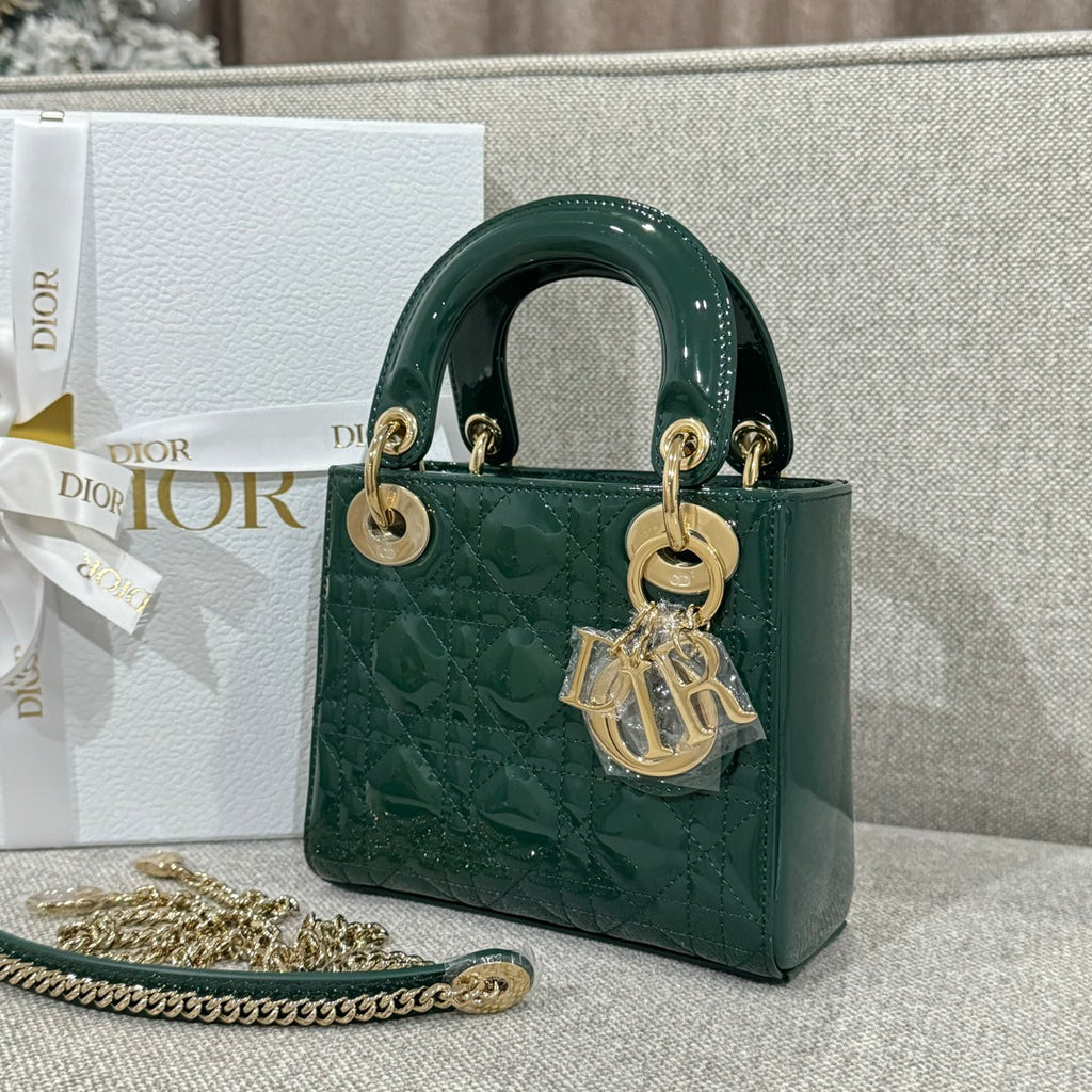 Small green Dior handbag with top handles, gold-tone rings, and logo charm