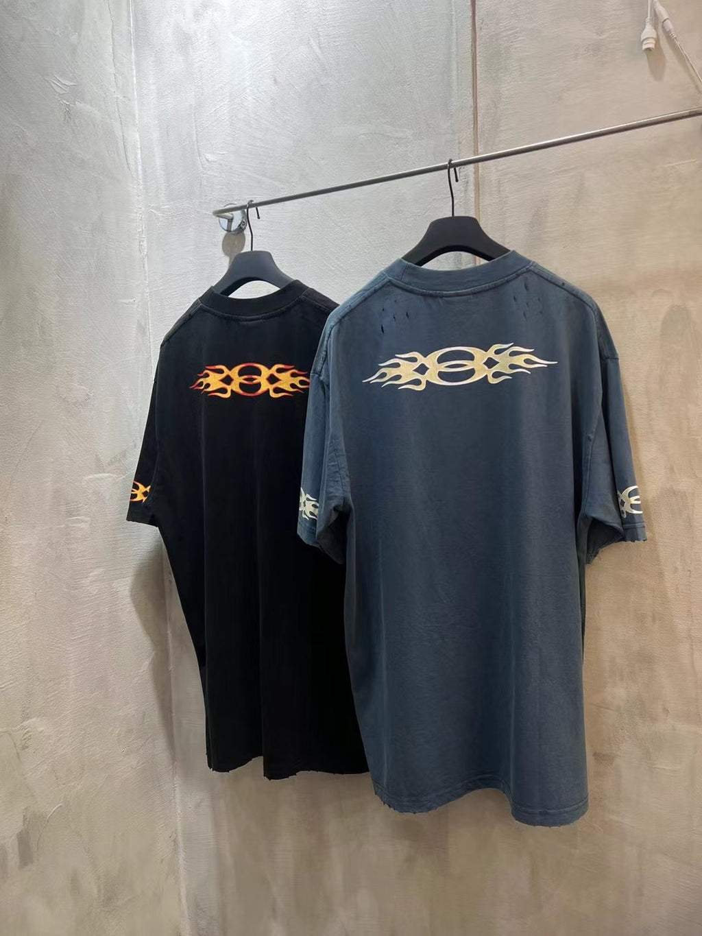 Black and blue Balenciaga T-shirts with orange flame logo, hanging together