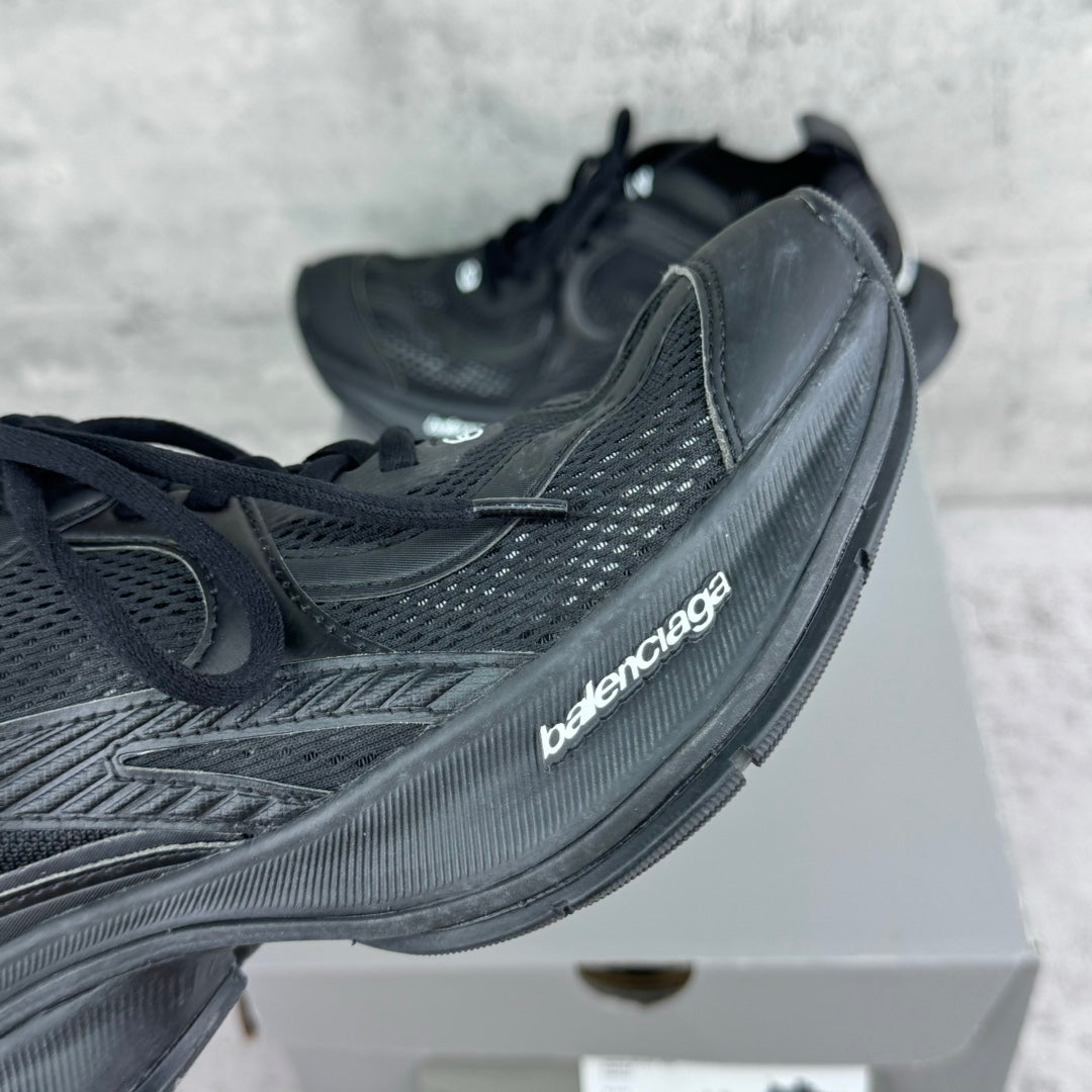 Close-up of dark gray/black lace-up sneaker with textured side panel and logo patch