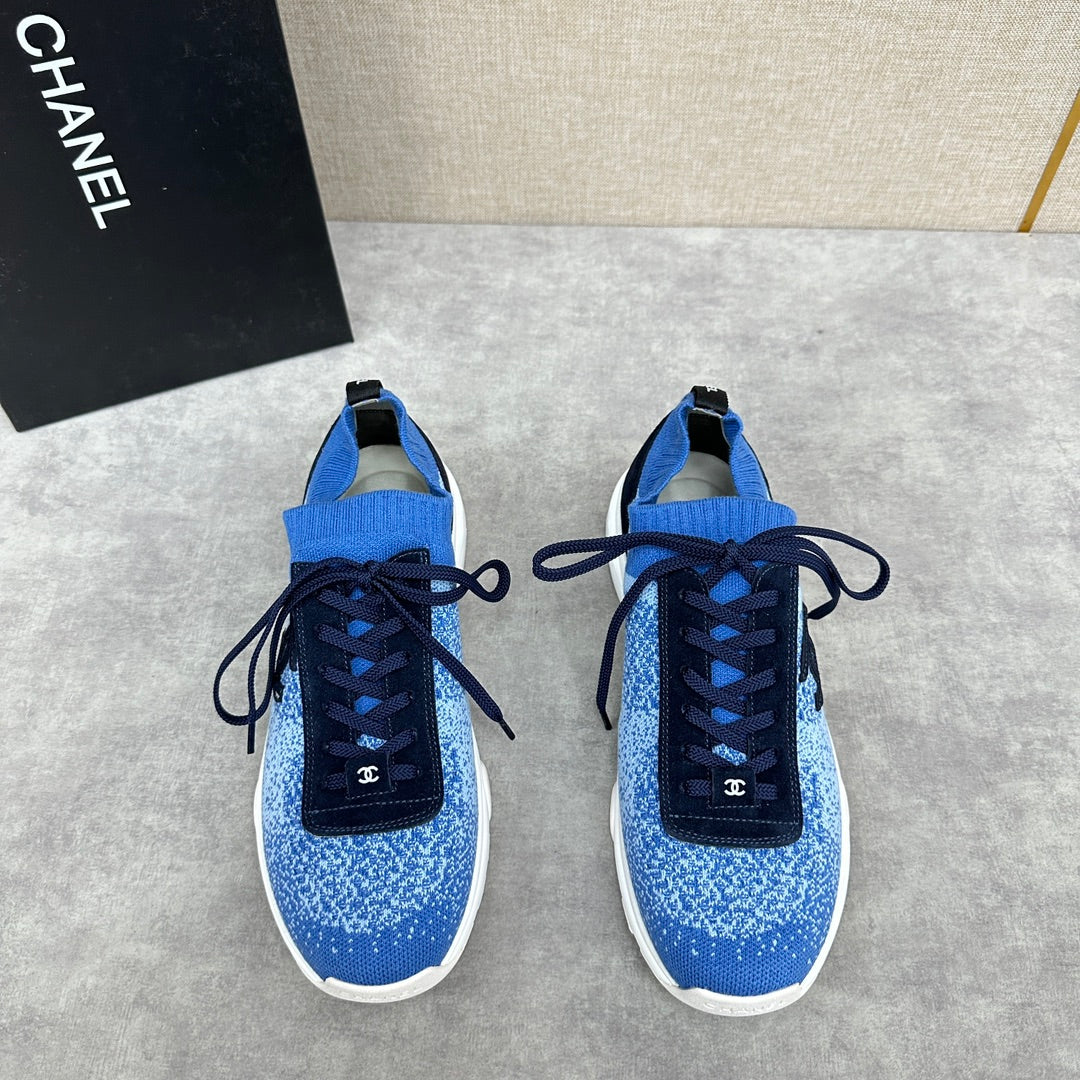 Unisex blue knit sneakers with dark navy laces, white sole, and black logo patch