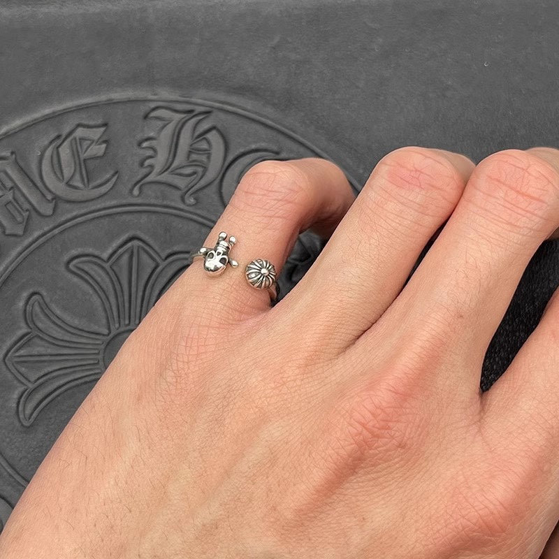 Silver-tone ring with daisy and skull charms on finger