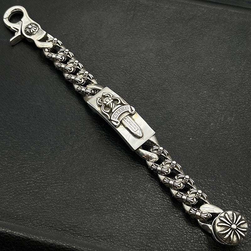 Silver-tone chain bracelet with ornate rectangular plate, braided links, and flower charm