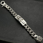 Silver-tone chain bracelet with ornate rectangular plate, braided links, and flower charm