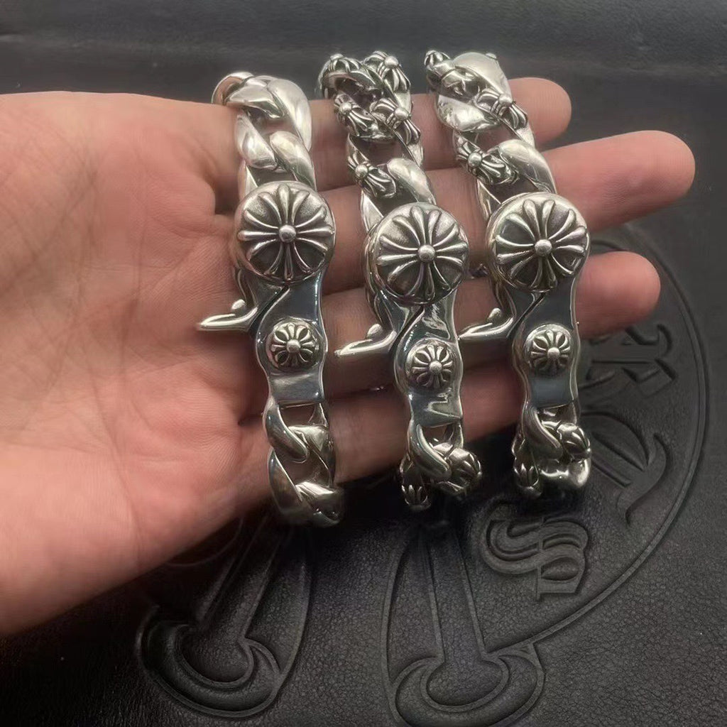 Set of three silver-toned chrome bracelets with twisted links and flower medallion details