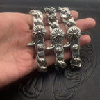Set of three silver-toned chrome bracelets with twisted links and flower medallion details