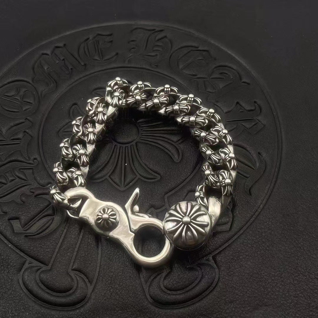 Silver-toned circular bracelet with twisted chain links and raised flower medallion charms