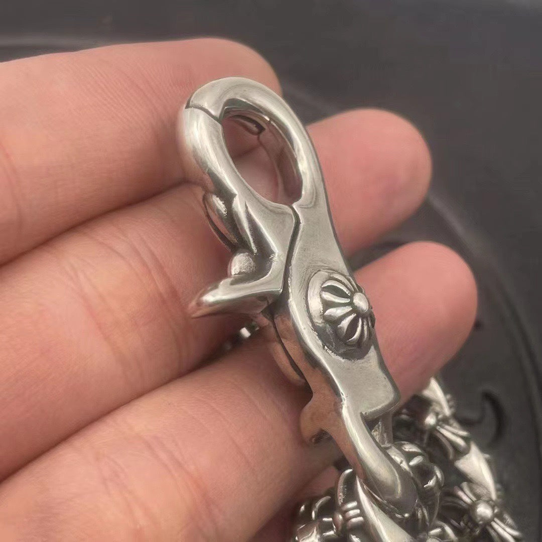 Silver-toned bracelet clasp detail with engraved flower centerpiece and twisted link segment