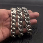 Three silver-toned bracelets with twisted chain links and flower accents, shown in hand