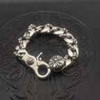 Silver-toned circular bracelet with twisted links and flower medallion charms at the ends