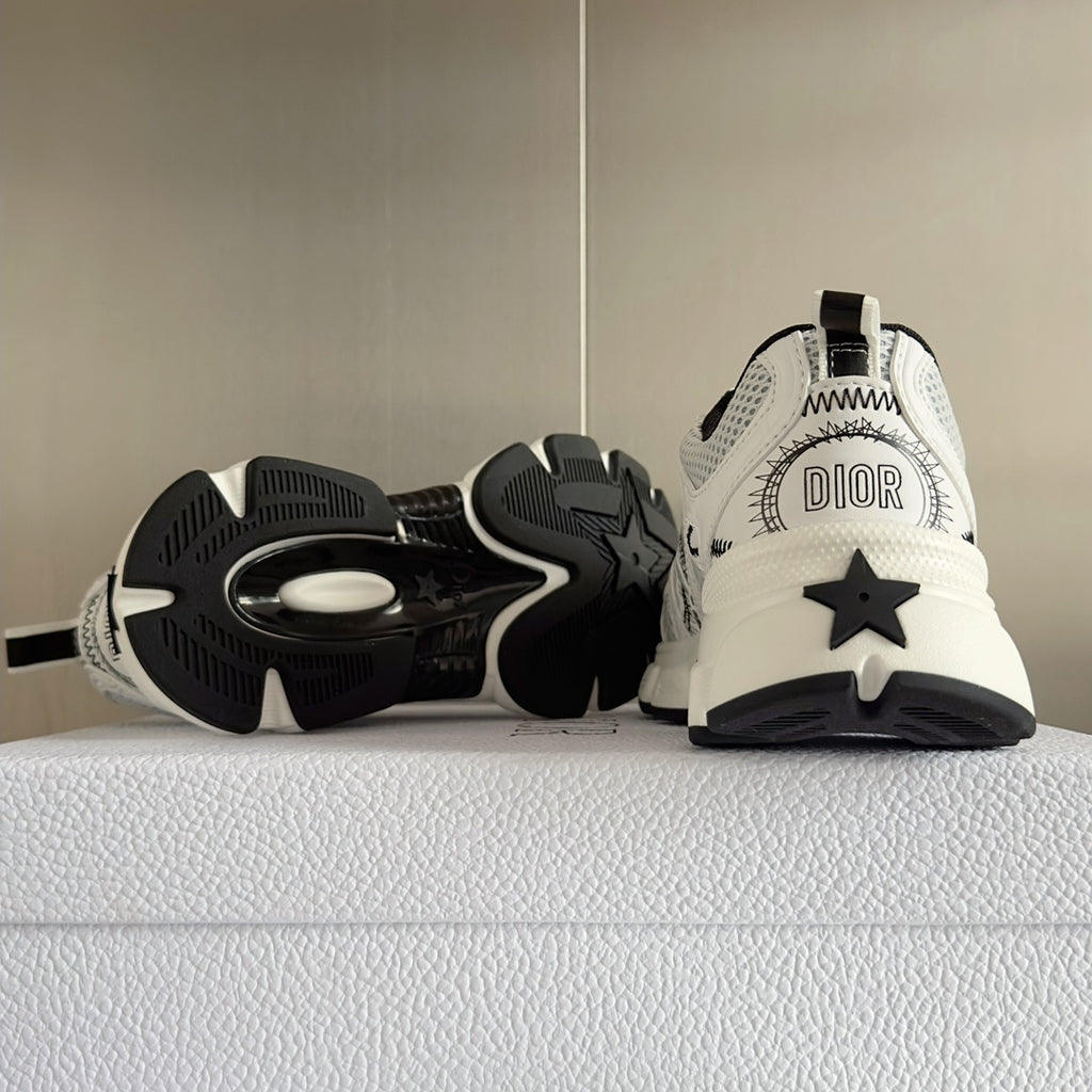 Unisex sneaker pair, showing white upper with black star motif and treaded outsole