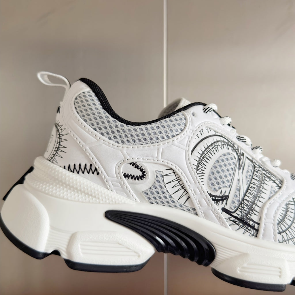 Unisex white lace-up sneaker close-up with black patterned stitching and chunky sole