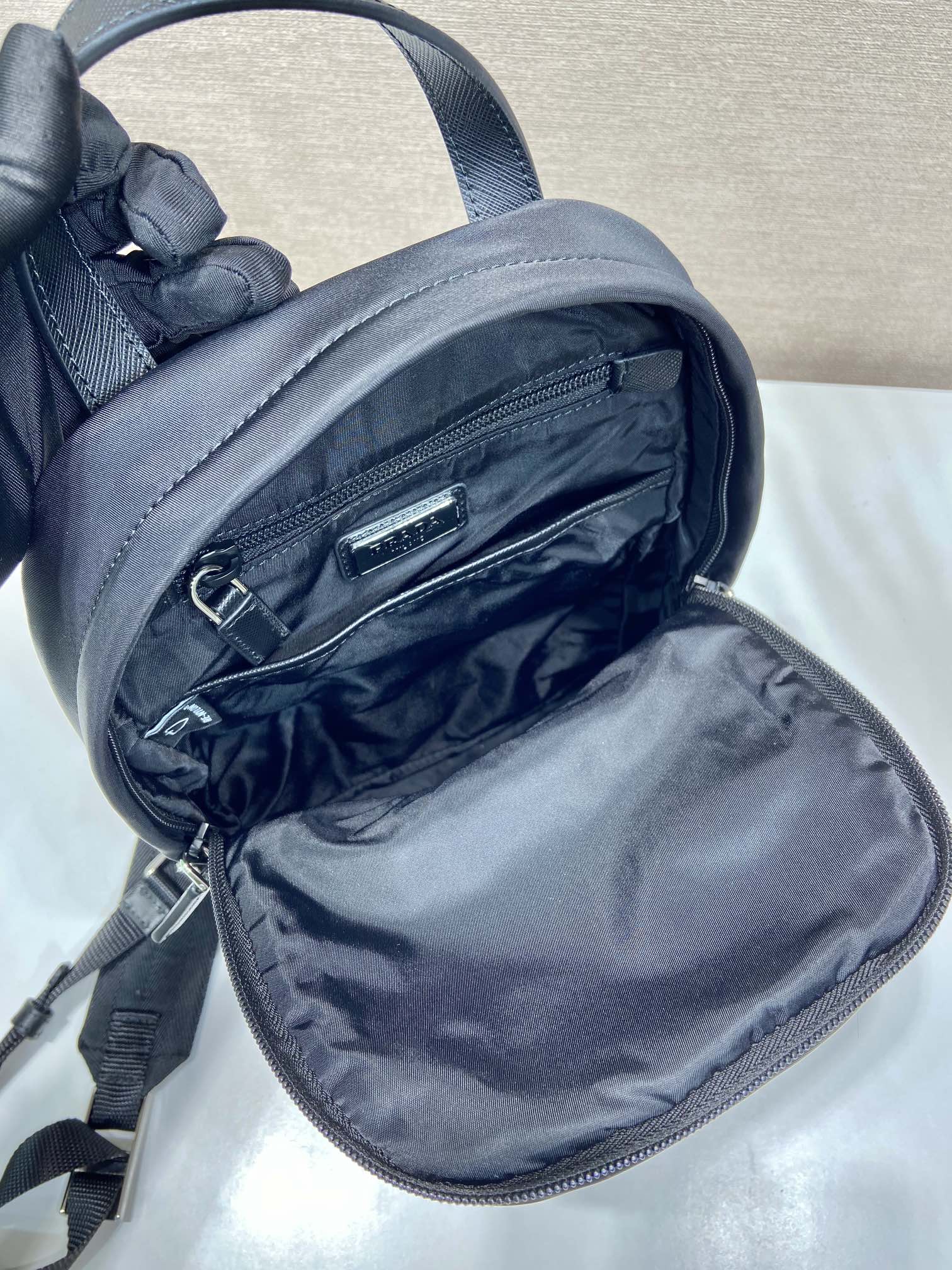 Black Prada mini backpack open with nylon lining and dual zipper pockets