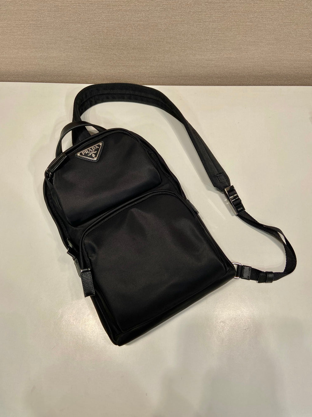 Black Prada mini backpack with adjustable shoulder strap, front zip pocket and logo