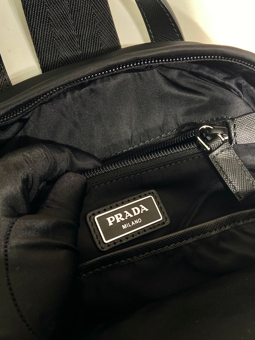 Prada Milan logo patch on black inner zip pocket, satin lining and zipper