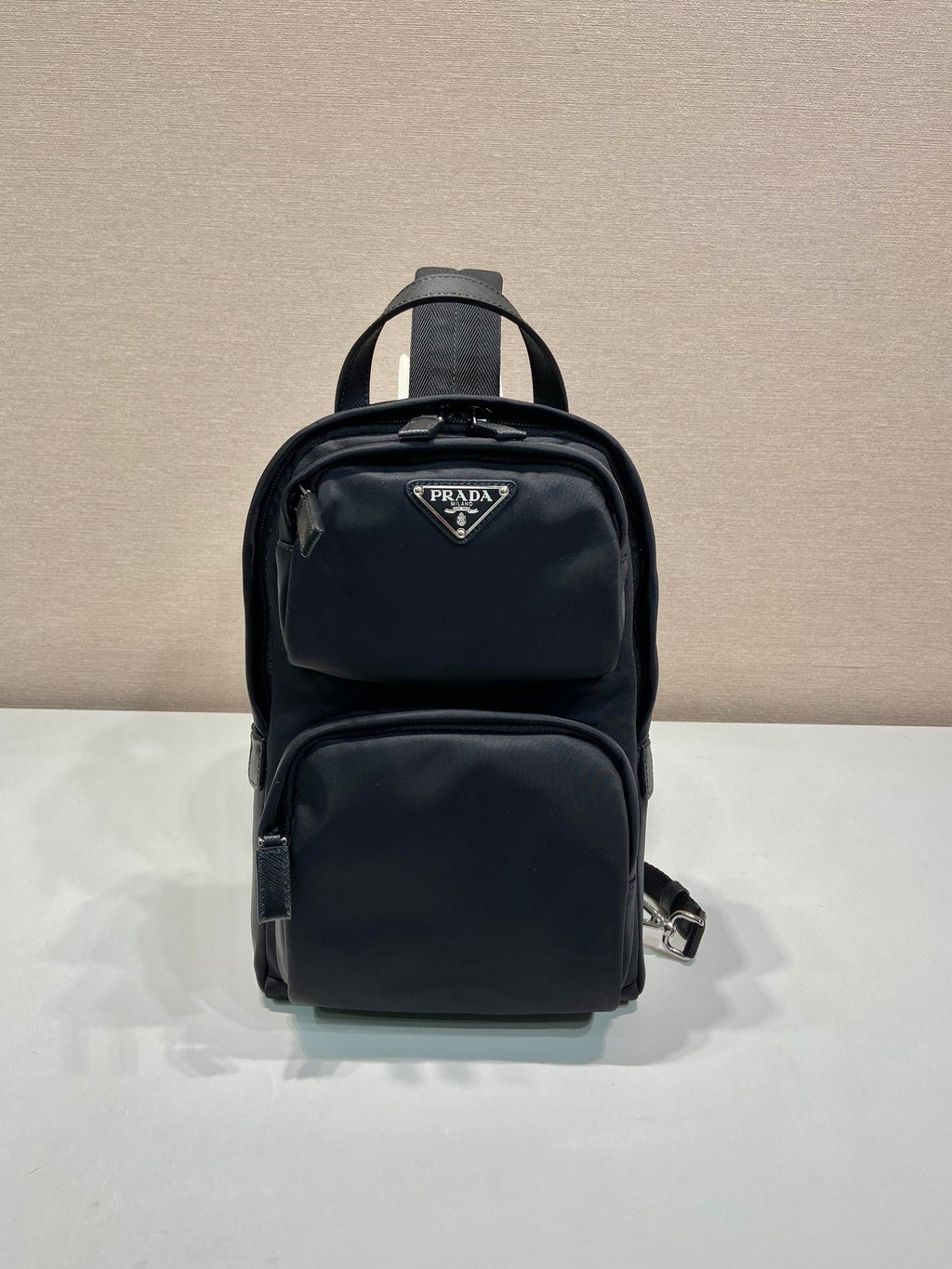 Black Prada mini backpack with zip front and top handle, logo patch on pocket