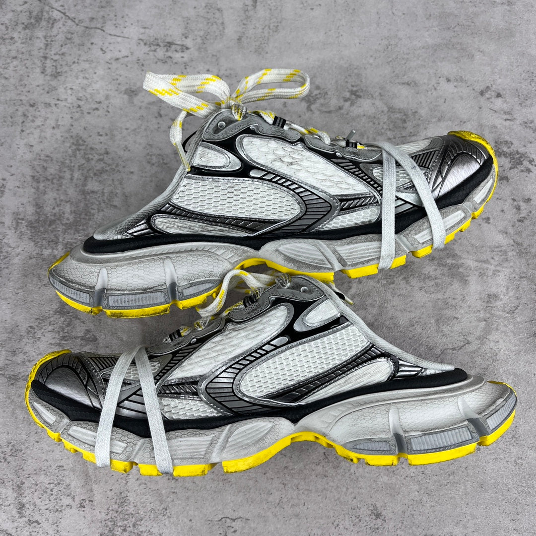 Gray and black chunky sneakers with white laces and yellow outsole trim, side view.