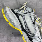 Gray chunky sneakers with textured panels, black accents, and white laces; yellow sole.